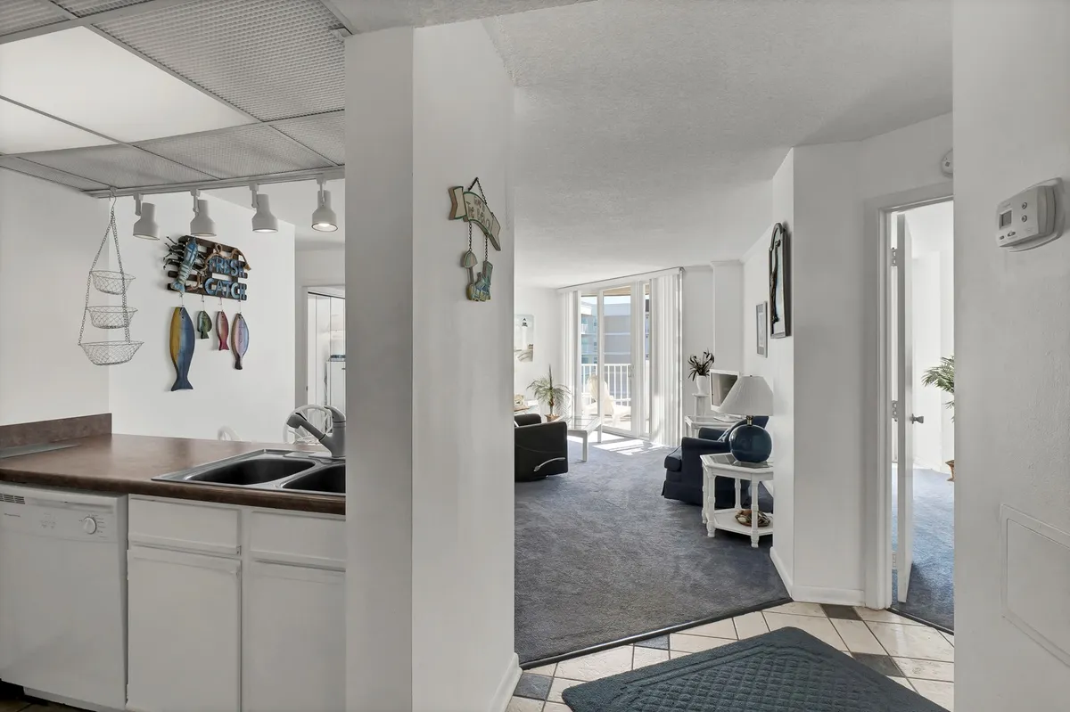 A wide-angle view of the open-concept kitchen and living area, featuring a kitchen with decorative fish art, a spacious living area, and large windows that bathe the space in natural light. The arrangement supports entertaining, family gatherings, and everyday relaxation.