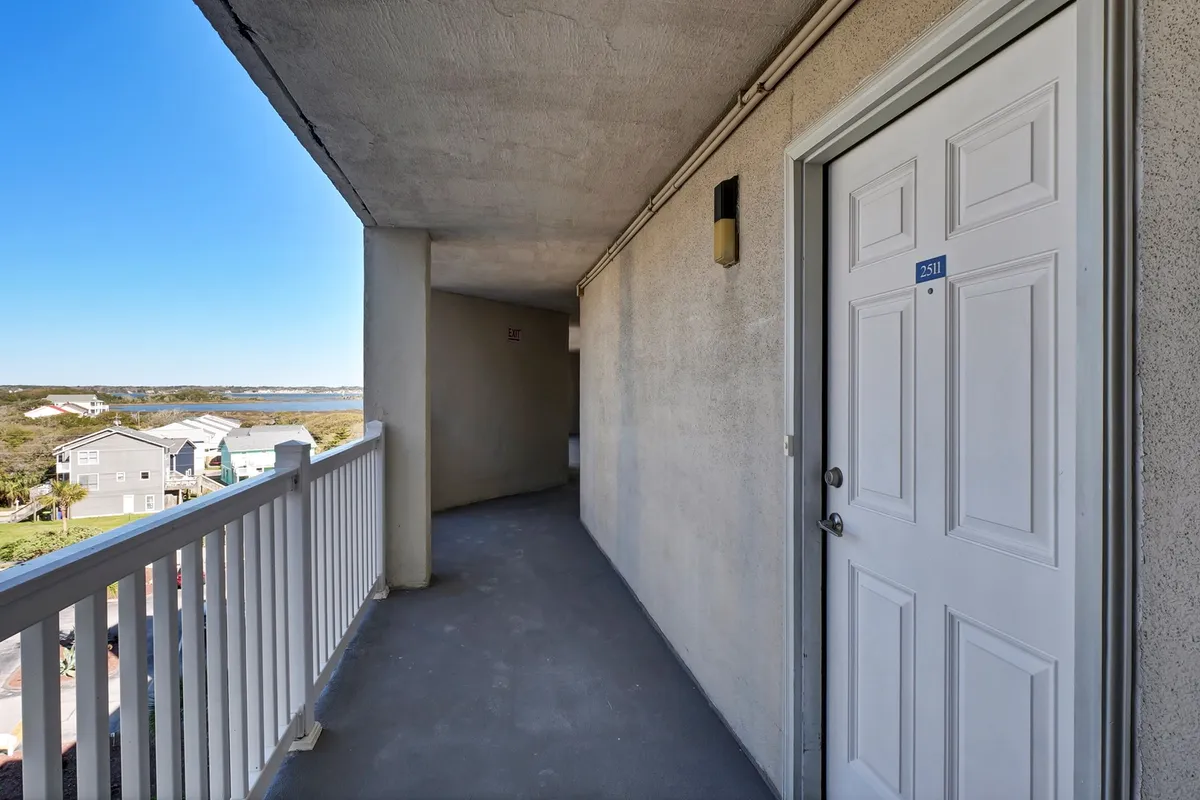 This exterior shot features a welcoming doorway and a balcony with a view, with a pathway leading through the space. The angle provides a sense of the connection between indoor comfort and outdoor enjoyment, suggesting easy movement between the two.