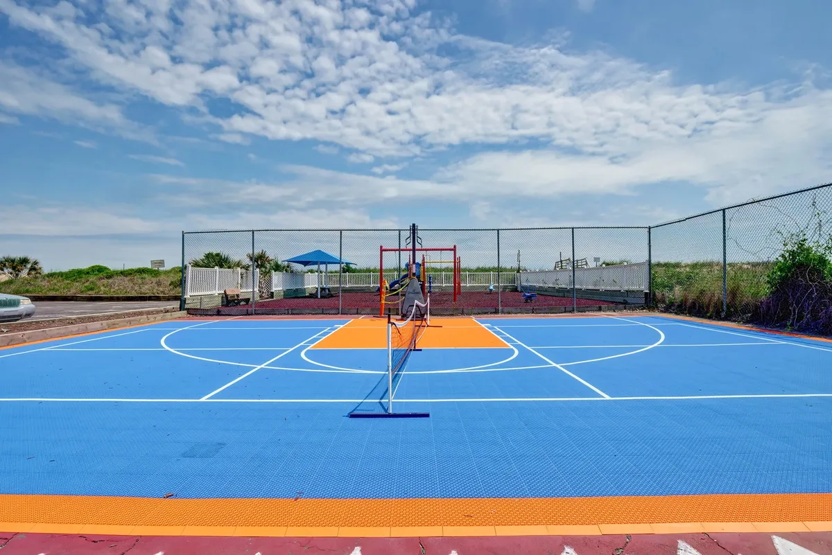 A vibrant exterior shot of colorful sports courts and a playground surrounded by greenery, featuring equipment for basketball, tennis, and plenty of space for children to play and families to gather.
