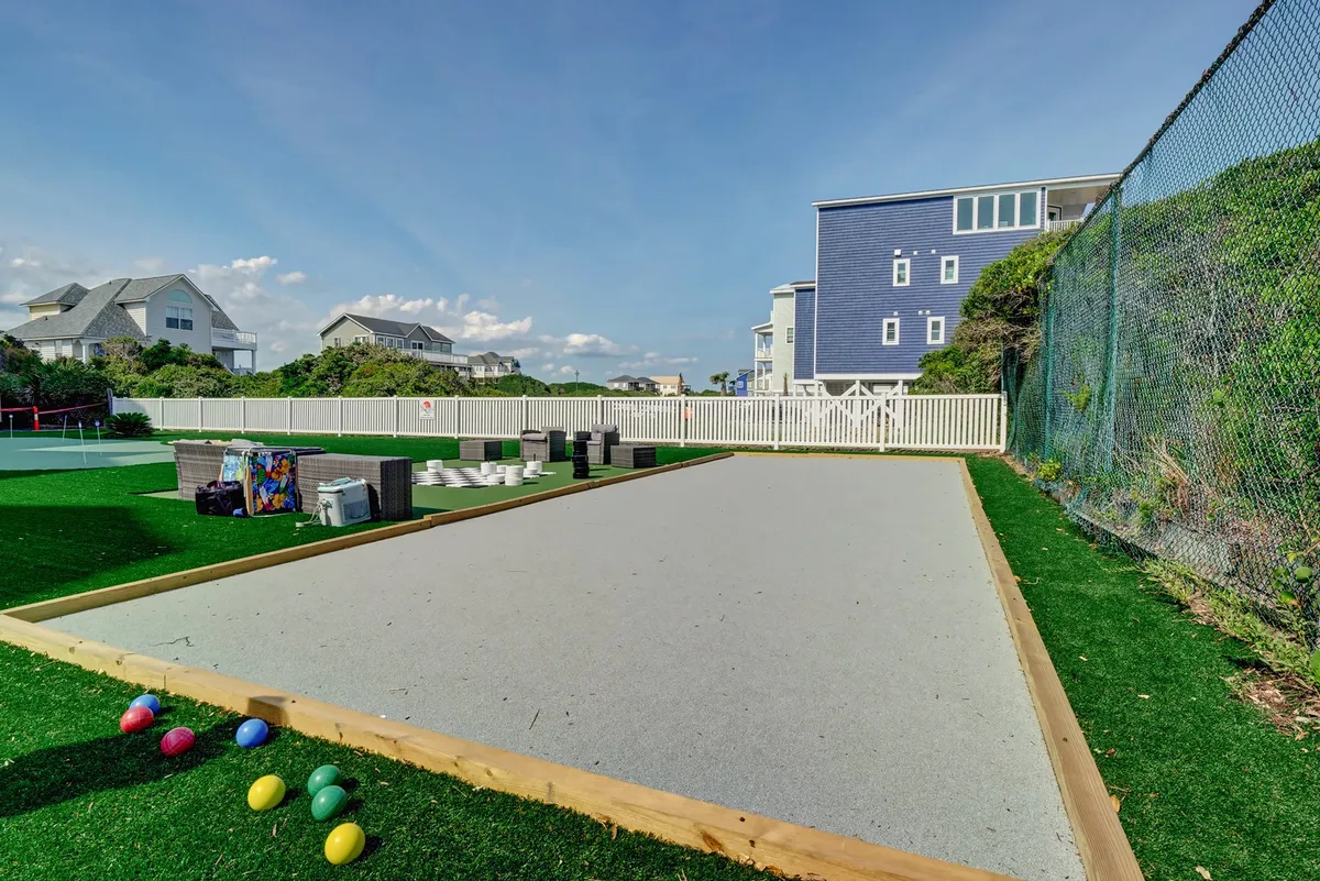 An exterior scene showcasing a bocce court with colorful bocce balls laid out on the court, surrounded by well-maintained properties. The open space is inviting for group activities and social recreation.